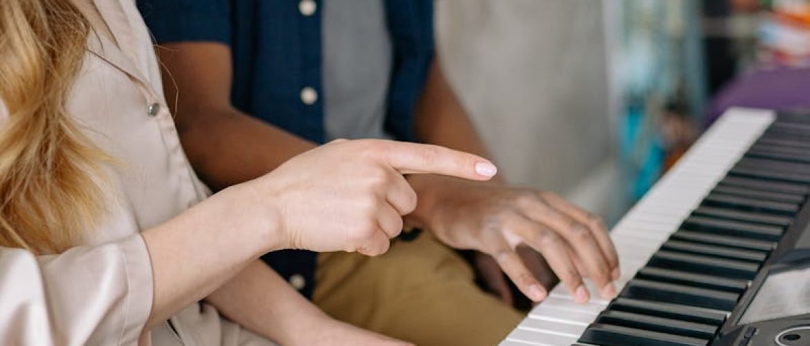 Young boy learning to play the piano with his music teacher at home.